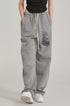 Model in black crop top and relaxed-fit grey sweatpants with graphic detail. Styled with white Air Force 1 sneakers