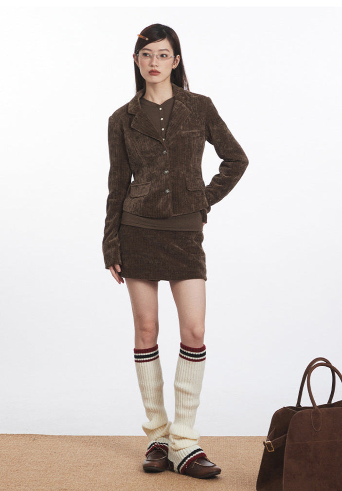 Model wears matching brown corduroy blazer and mini skirt set with cream knee-high socks and loafers.