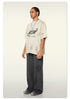Side view of model in loose Beattube t-shirt, wide charcoal pants, and gray sneakers