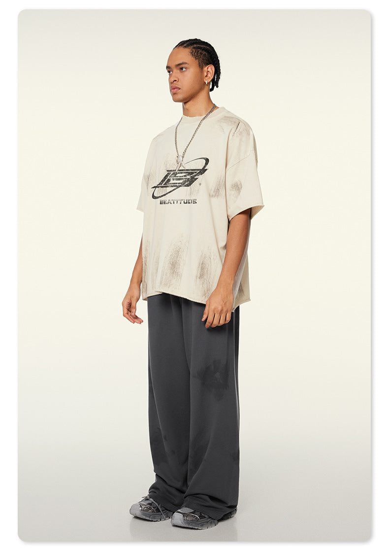 Side view of model in loose Beattube t-shirt, wide charcoal pants, and gray sneakers
