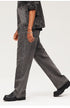Walking pose highlighting wide-leg washed black jeans with chunky boots, demonstrating movement and fit