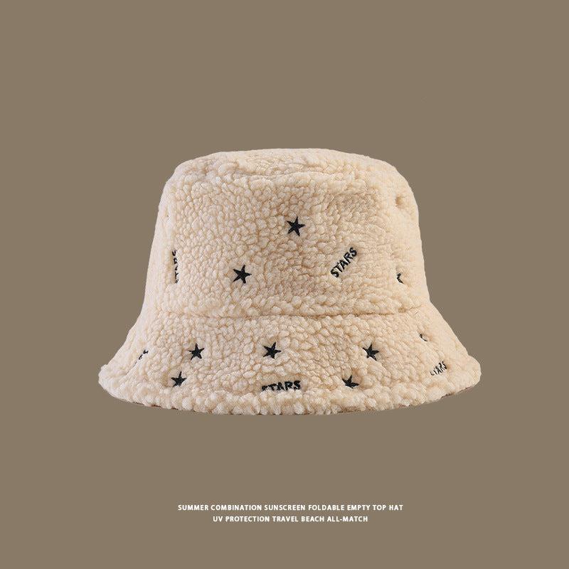 Cream teddy fleece bucket hat with embroidered black stars and 'STARS' text pattern displayed against taupe background