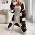 A woman in wine red, white and beige striped cardigan styled with white cami and white jeans, posing against white background