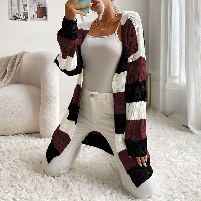 A woman in wine red, white and beige striped cardigan styled with white cami and white jeans, posing against white background