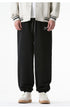 A close-up of black jogger sweatpants featuring a drawstring waist, elastic cuffs, and a small embroidered logo on the left thigh