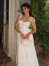 Woman in a white dress holding a pink handbag outdoors.