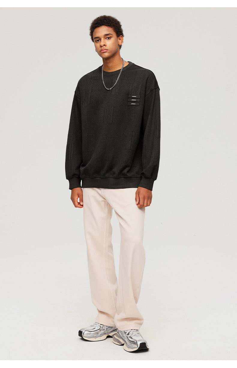 Full-body shot of male model in black textured sweatshirt with white pants and gray sneakers