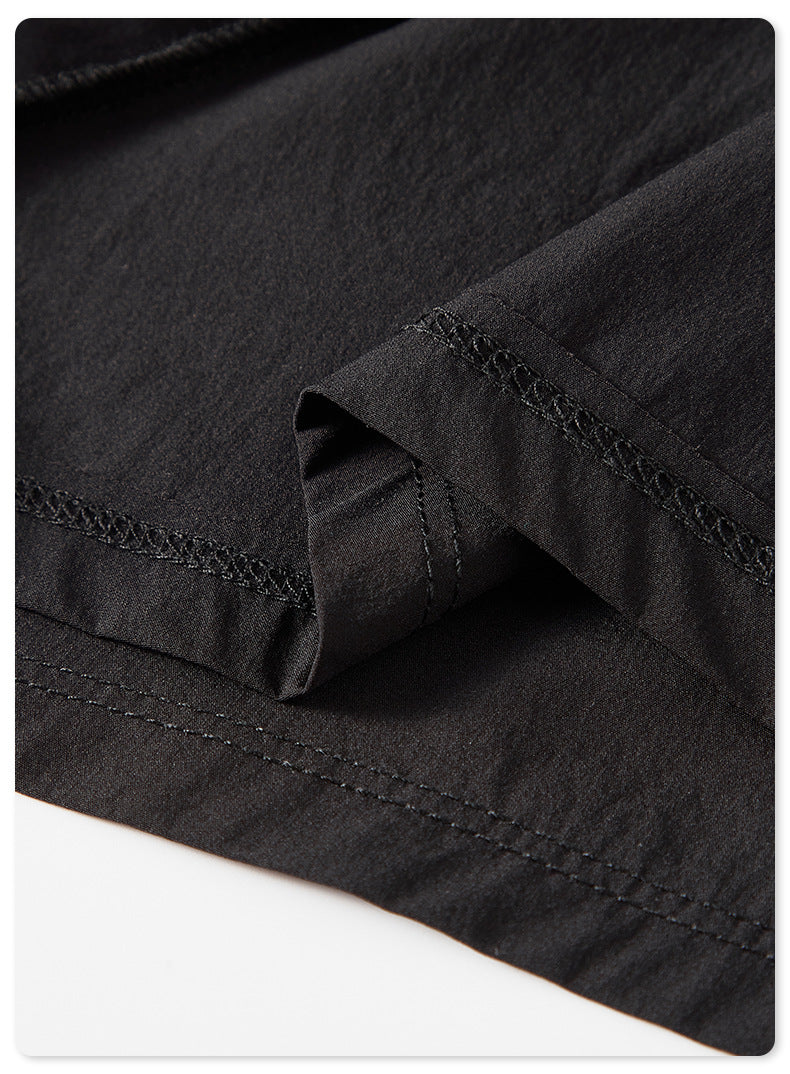 Close-up of black fabric hem detail with stitching against white background