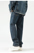A model is wearing relaxed-fit dark wash denim jeans with white platform sneakers, posed in profile against a plain backdrop