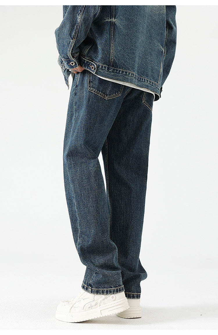 A model is wearing relaxed-fit dark wash denim jeans with white platform sneakers, posed in profile against a plain backdrop