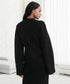Sleek black cardigan with side view of model, minimal white interior backdrop