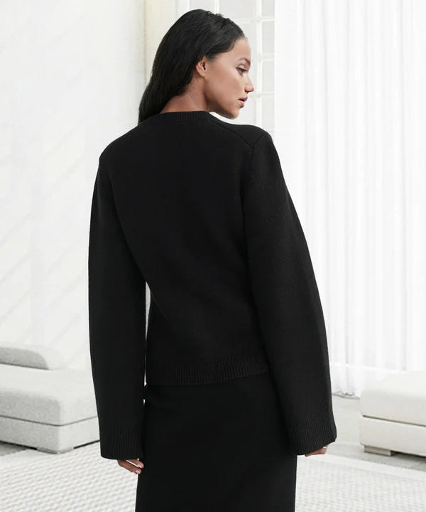 Sleek black cardigan with side view of model, minimal white interior backdrop