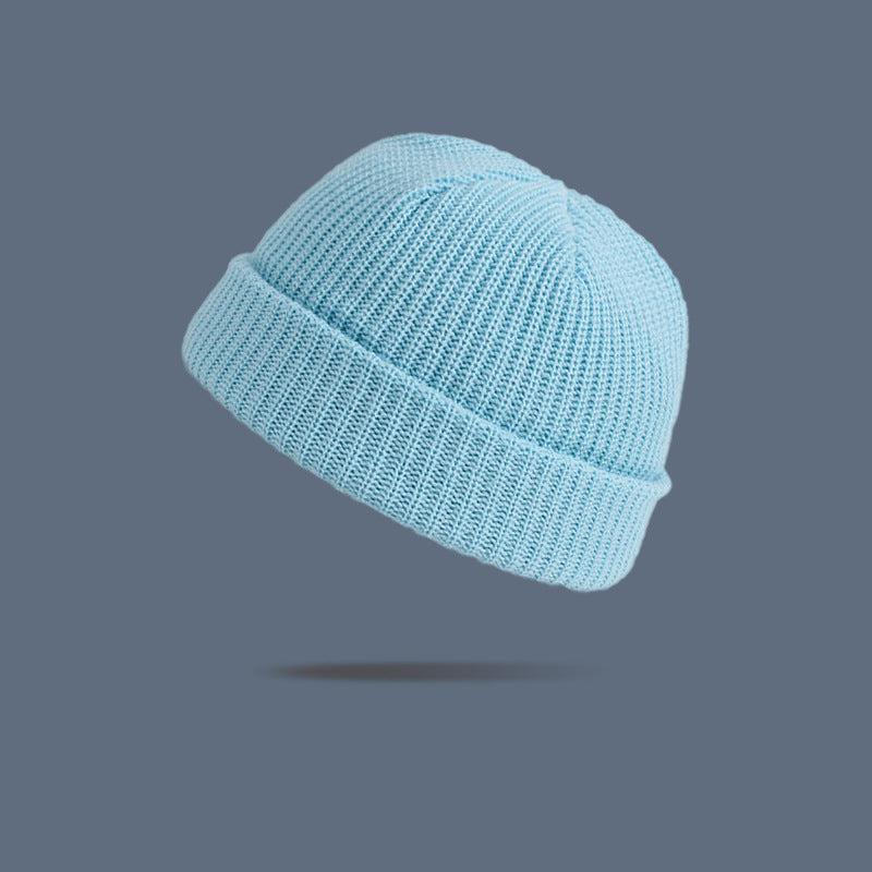 A light blue ribbed knit beanie with folded cuff floating against slate gray background, showing soft pastel winter accessory