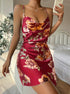 A model wearing burgundy floral print satin slip dress with cowl neckline, taking mirror selfie in bedroom setting