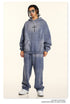 Full-length shot of gray graphic hoodie and sweatpants set, styled with white sneakers and silver chain necklace