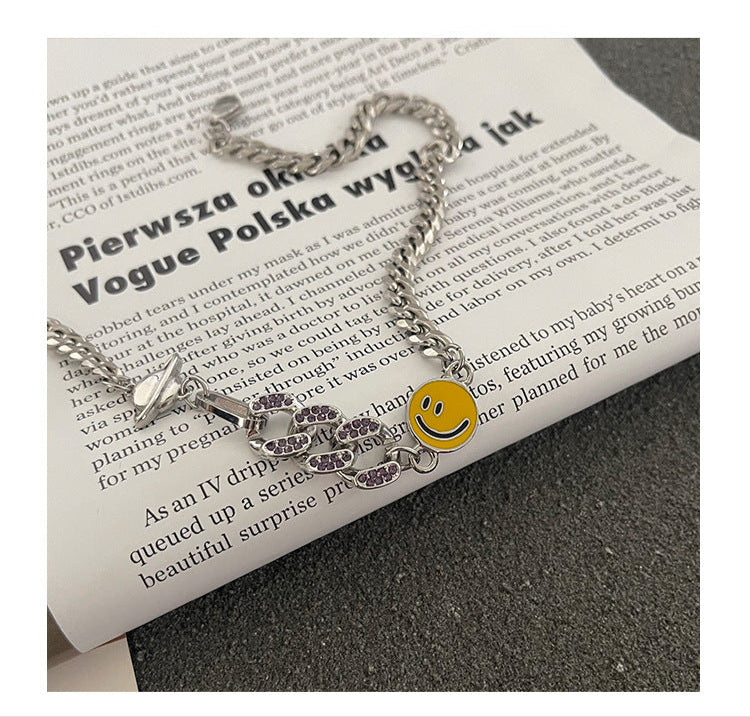 Close-up detail of Cuban chain necklace with smiley charm and crystal snake accent displayed on text page, showing texture and finish of metal