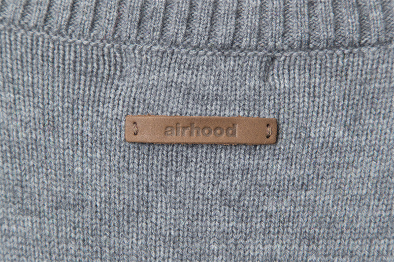 Tan leather label reading 'airhood' stitched onto grey knit fabric.