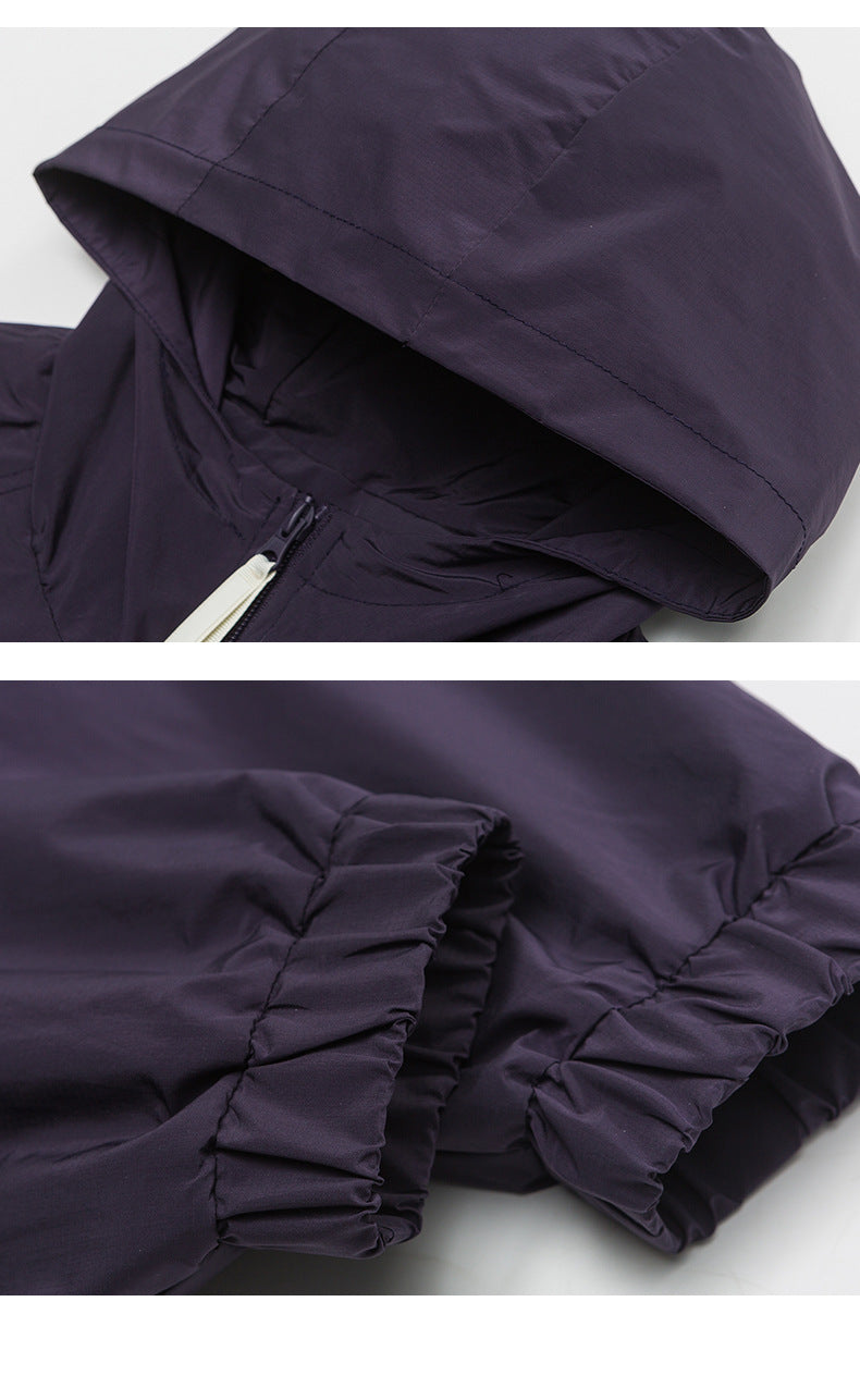 Close-up detail of purple windbreaker jacket showing hood construction and elastic cuff details against white background.