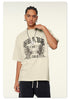 Close-up of model wearing cream t-shirt with gothic "BRAVE ABLE" and tiger graphic print, silver chain necklace, hand touching shoulder against neutral backdrop