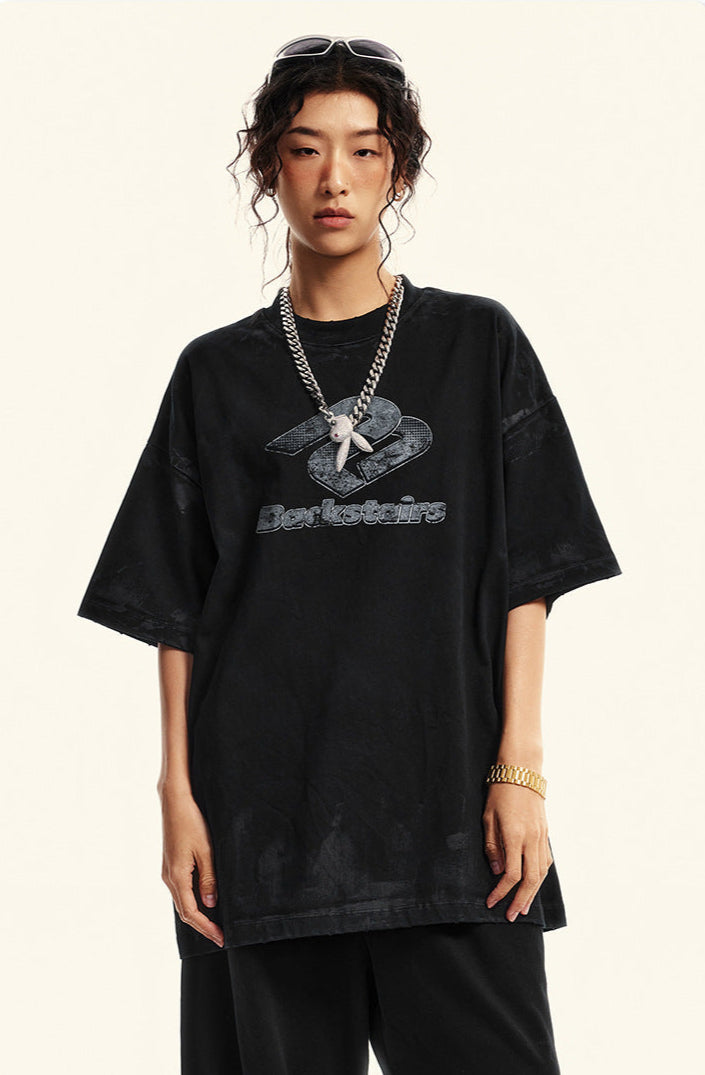 Model with sunglasses atop head wearing black Backstairs logo tee and silver chain necklace