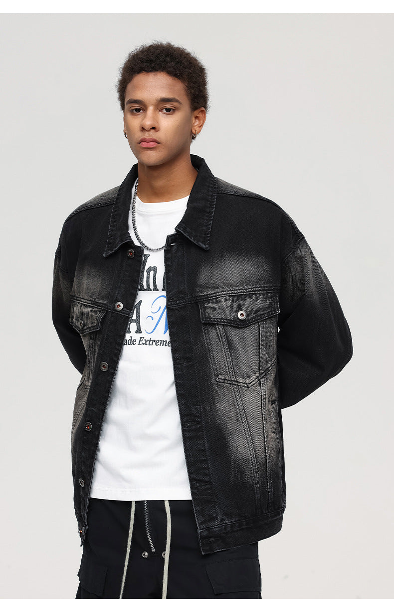 Close-up shot of a male model in a black washed denim jacket over a white graphic T-shirt and cargo pants