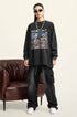 A female model wears a black oversized "RECOLLECT" sweatshirt, black cargo pants, and sneakers, standing in front of a leather chair