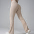 Side view of cream-colored flared yoga pants with white sneakers, showing leg movement against gray background