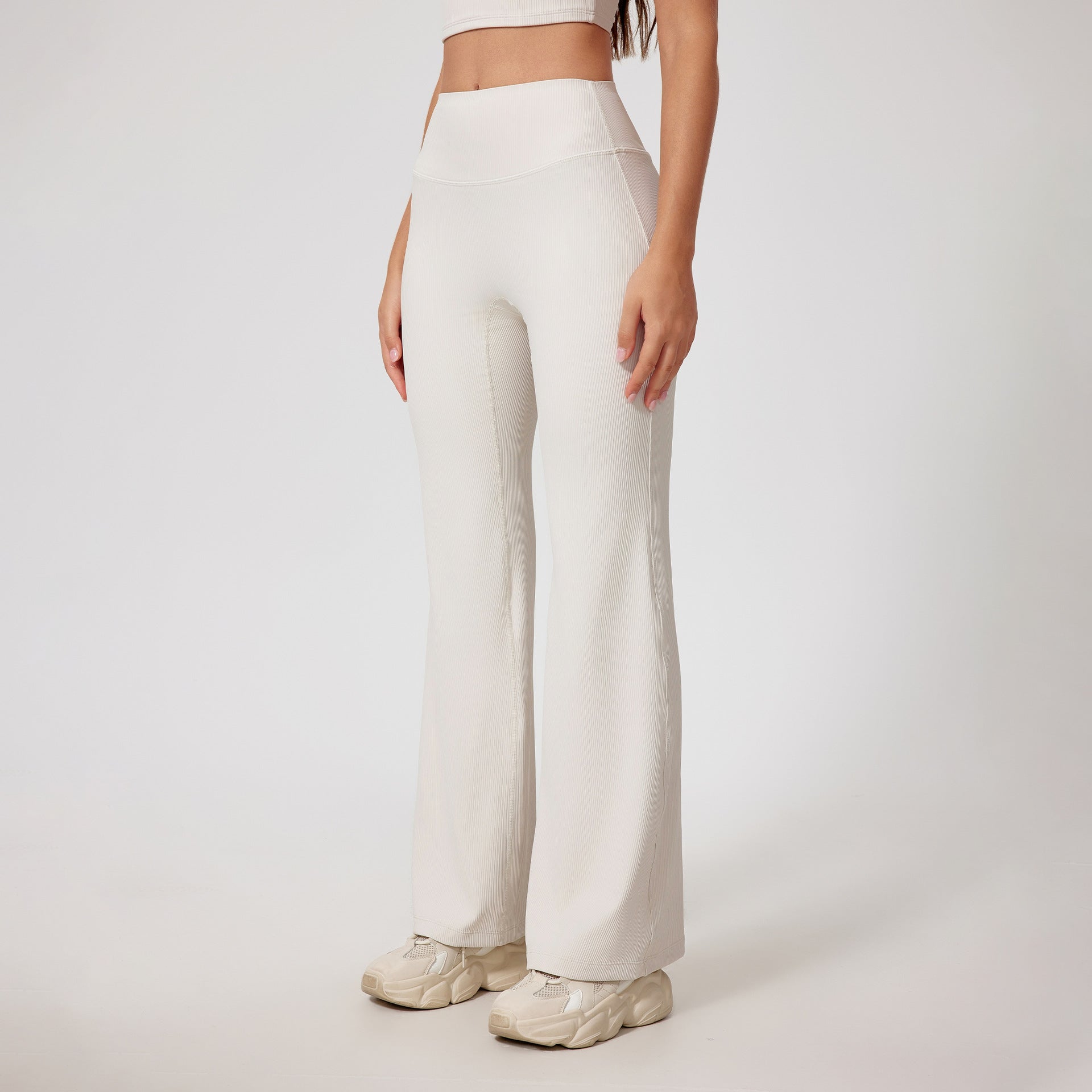 Cream ribbed yoga pants with high waistband, wide leg silhouette, stretchy fabric, cream chunky sneakers, partial crop top visible