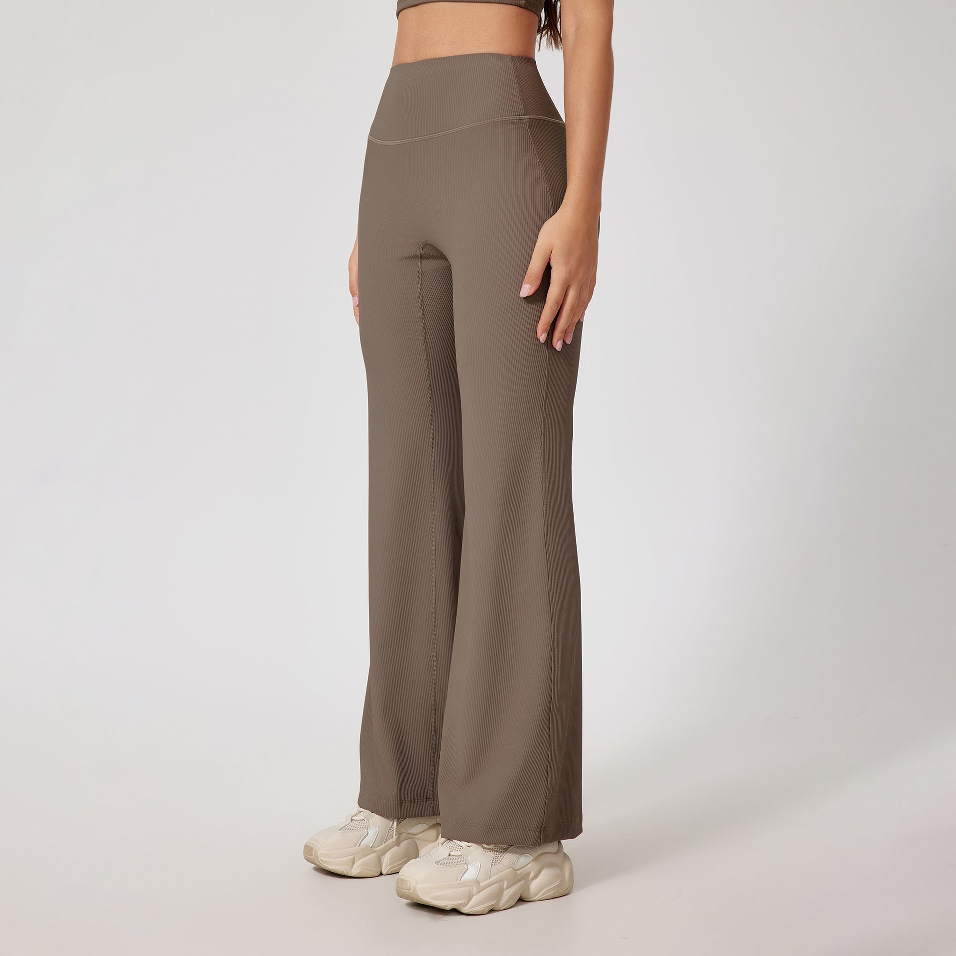 Taupe ribbed yoga pants with high waist design, wide leg silhouette, seamless construction, neutral chunky sneakers, minimal styling