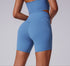 A model is posing with blue compression bike shorts featuring contoured seams and high-waisted silhouette against light gray background