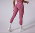 Model wearing dusty rose athletic leggings with ruched back detail, paired with matching crop top and white sneakers