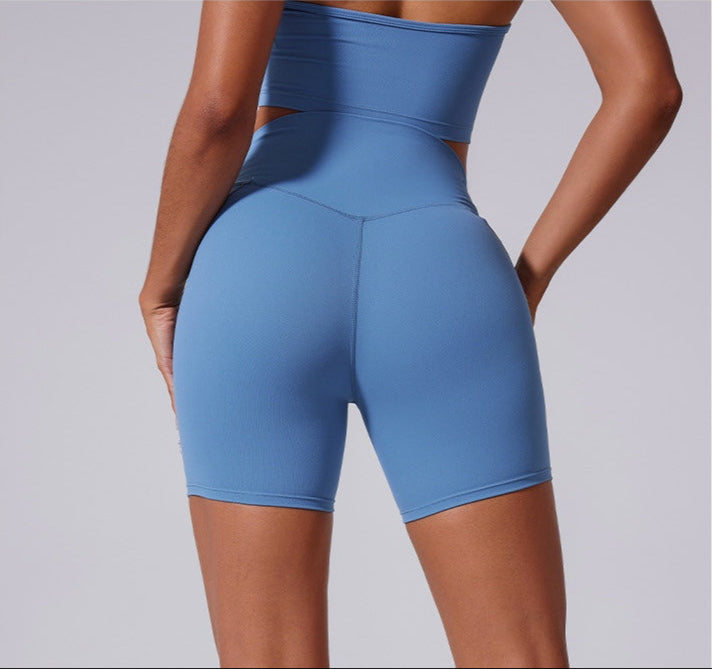 A model is showing back view of blue seamless biker shorts with high-waisted design and supportive compression fit against neutral backdrop