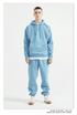 Male model with short hair wearing a sky blue sweatsuit with hoodie, white undershirt, and matching joggers