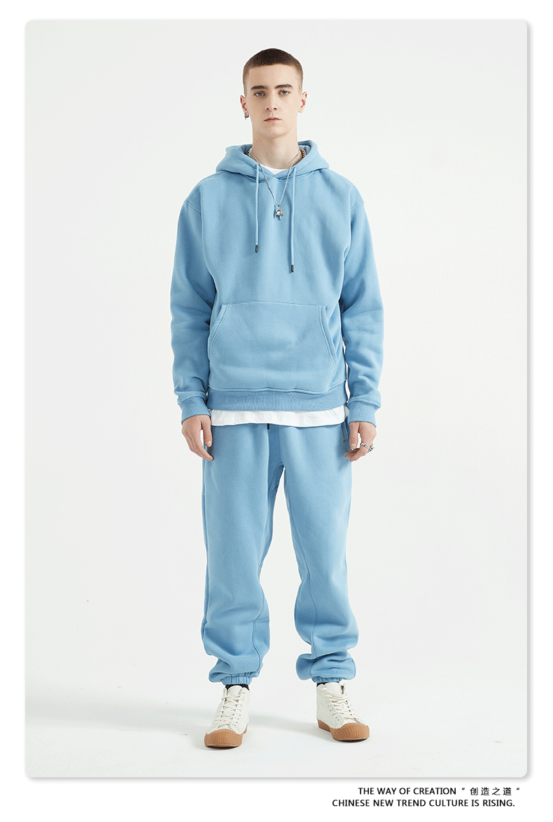Male model with short hair wearing a sky blue sweatsuit with hoodie, white undershirt, and matching joggers
