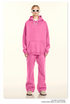 Model in bright pink hoodie and matching sweatpants with white textured sunglasses and beige shoes
