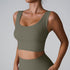 A woman wearing an olive green ribbed scoop neck sports bra with thick straps and seamless construction paired with matching high-waisted bottoms