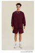 Man in burgundy sweatshirt and shorts set with sunglasses, chain necklace and white sneakers