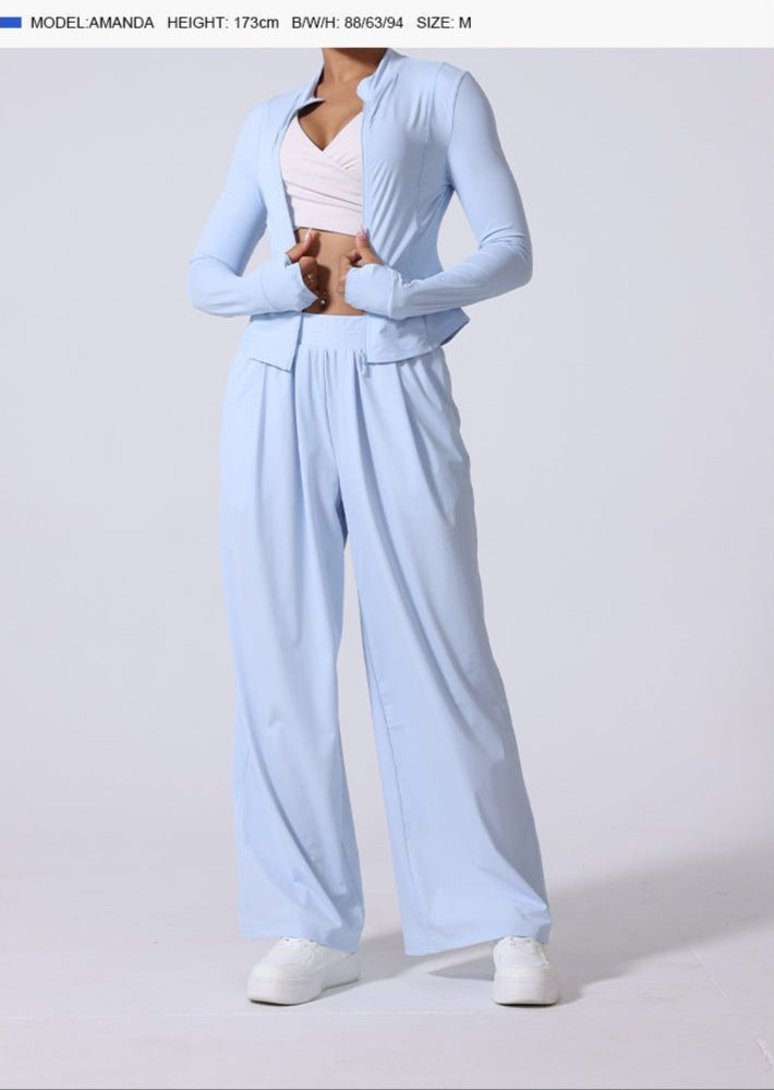 Model wearing light blue jacket, matching wide-leg pants and white crop top with white platform sneakers