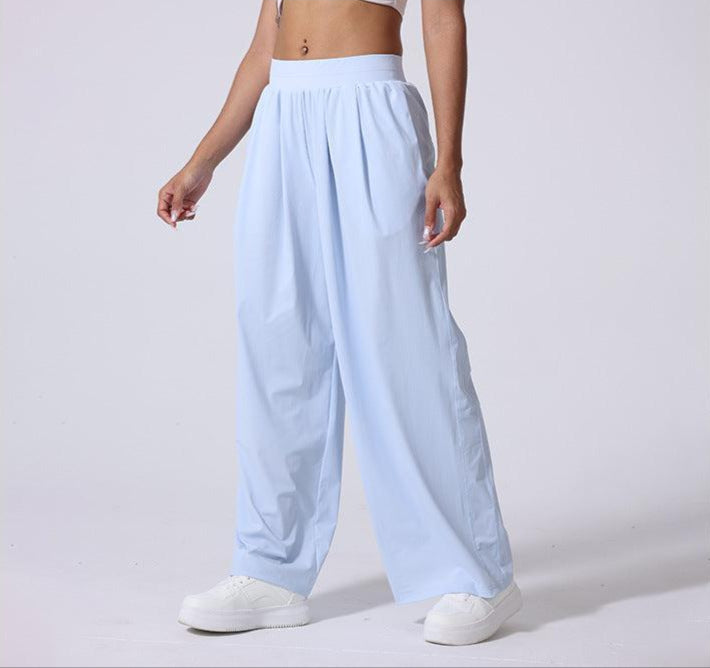 Side view of light blue wide-leg lounge pants with high waist, paired with white sneakers and crop top