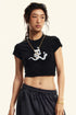 Black cropped t-shirt featuring a white devil girl and snake graphic, worn with black sweatpants and accessories