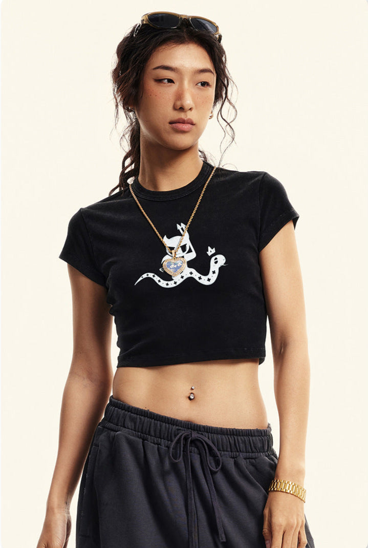 Black cropped t-shirt featuring a white devil girl and snake graphic, worn with black sweatpants and accessories