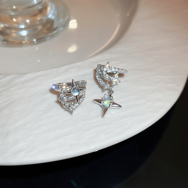 Silver ear cuffs with star designs and moonstone accents displayed on white ceramic plate