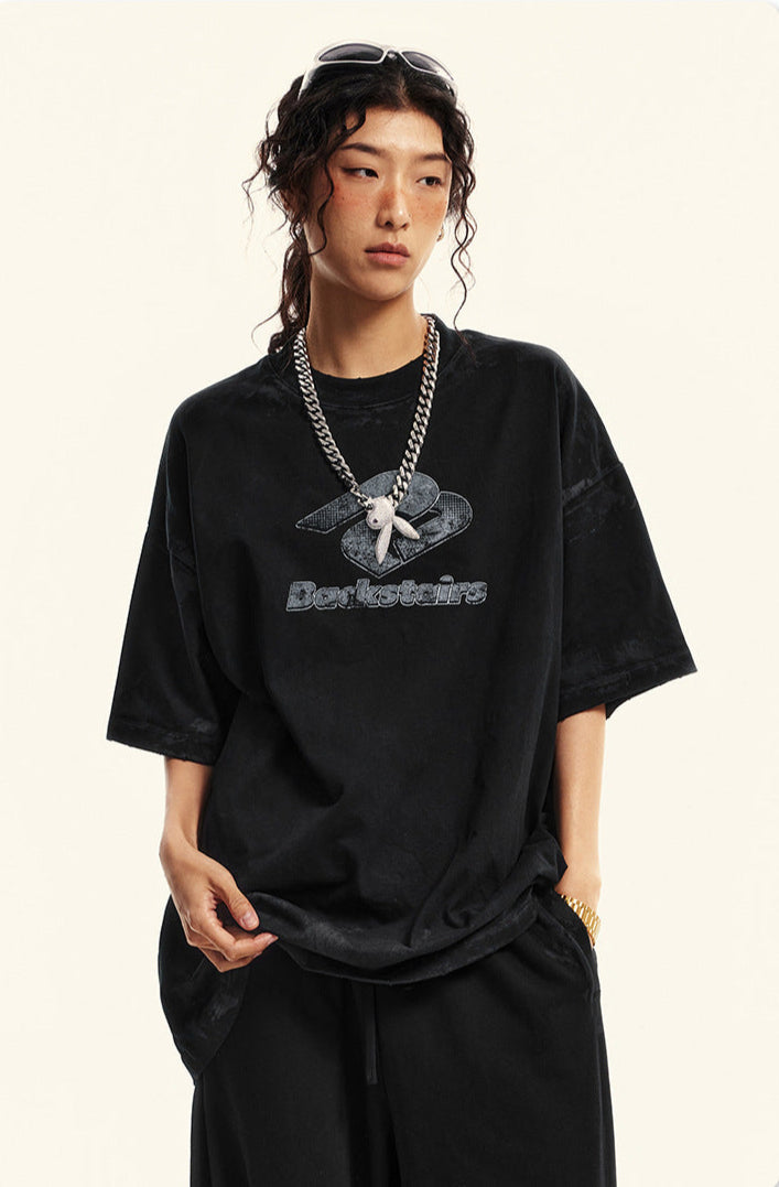 Side profile of model in black Backstairs t-shirt with logo and relaxed pants