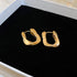 Abstract Gold Hoop Earrings – Unique gold hoop earrings with an irregular, sculptural design, placed in a black jewelry box