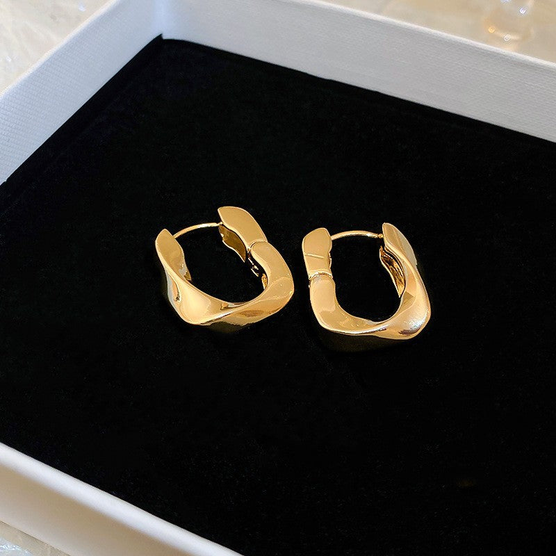 Abstract Gold Hoop Earrings – Unique gold hoop earrings with an irregular, sculptural design, placed in a black jewelry box