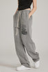 Model in black crop top with relaxed-fit grey sweatpants featuring drawstring waist and side pockets. Paired with white sneakers