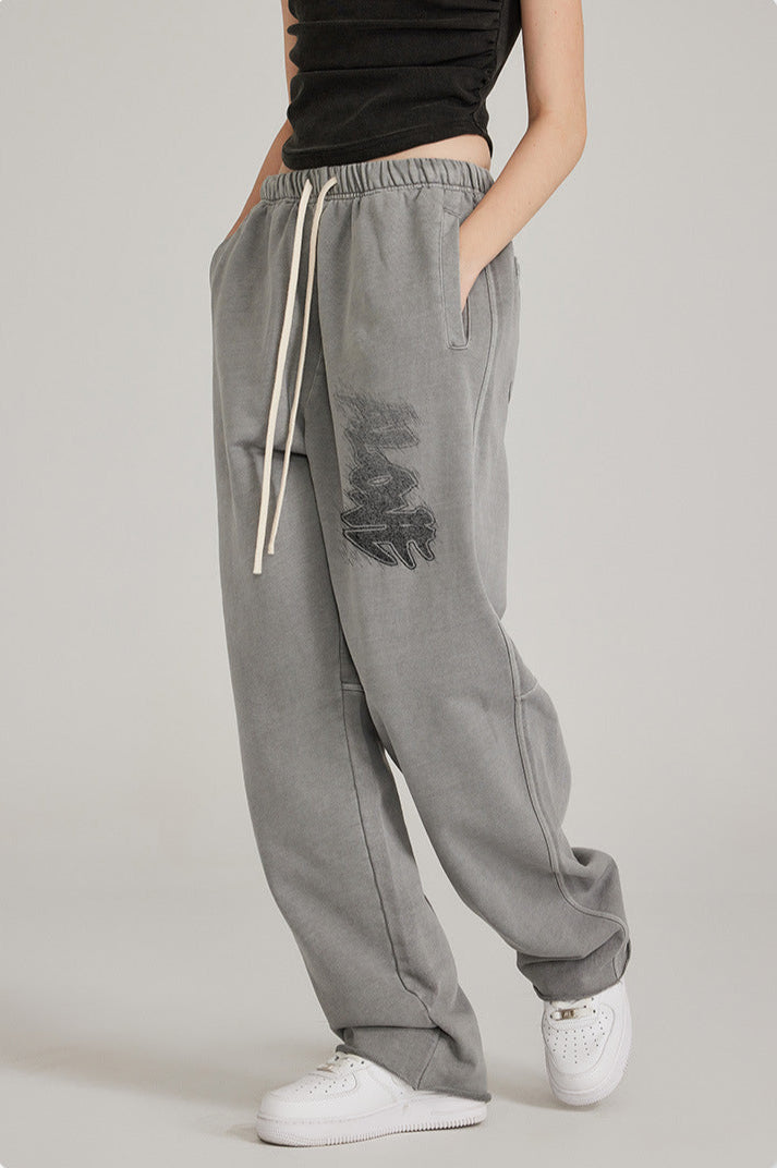 Model in black crop top with relaxed-fit grey sweatpants featuring drawstring waist and side pockets. Paired with white sneakers