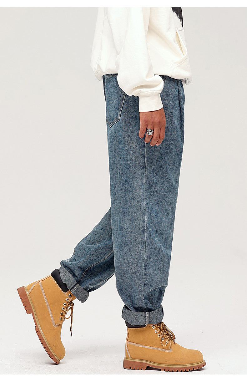 Close-up of jeans waistband showing metal button closure and elastic panel detail on medium-wash denim