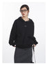 Close-up detail of black cotton hoodie showing metallic snap closures, embroidered eye logo, and kangaroo pocket