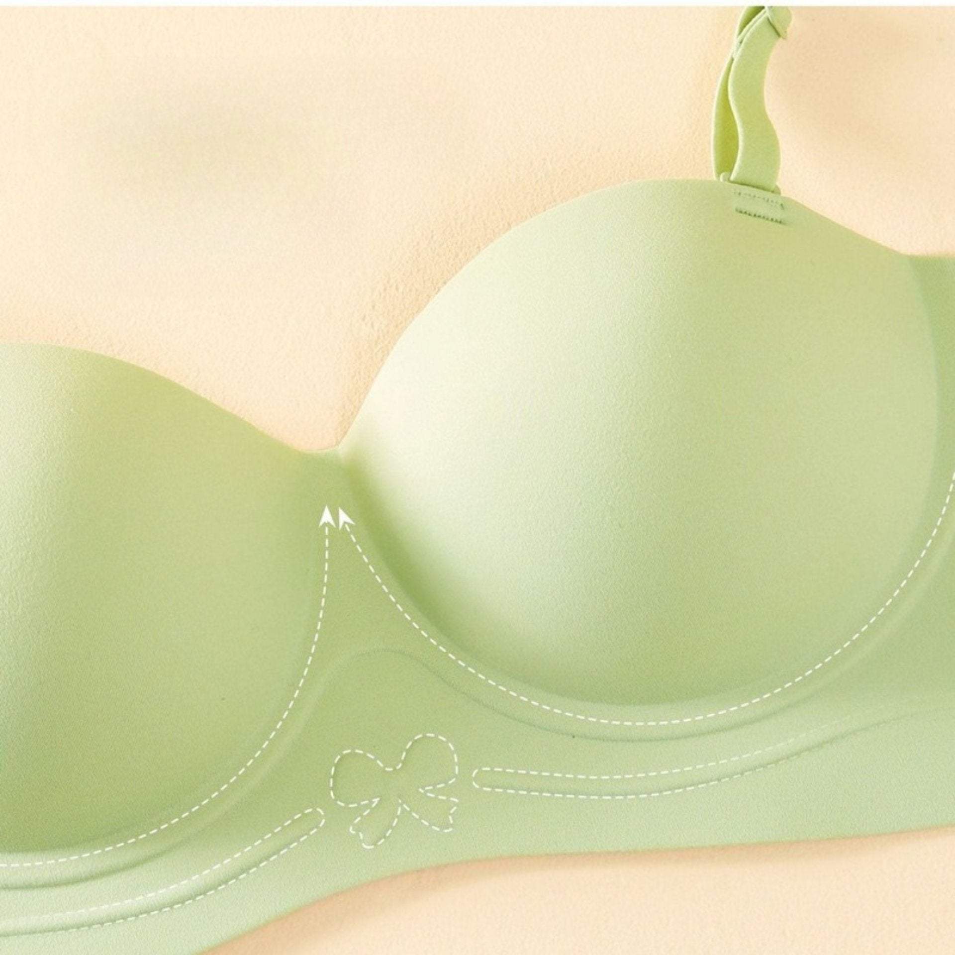 Close-up of a light green bra’s molded cup with a butterfly detail, highlighting smooth, seamless support.